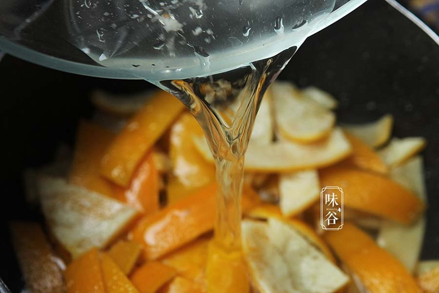 Tiếp đó, bóc vỏ cam, dùng thìa cạo sạch lớp màng trắng bên trong, cạo càng sạch thì càng không bị đắng. Cho vỏ cam vào nước sôi ngâm trong 10 phút để loại bỏ dư lượng thuốc bảo vệ thực vật và vị đắng.