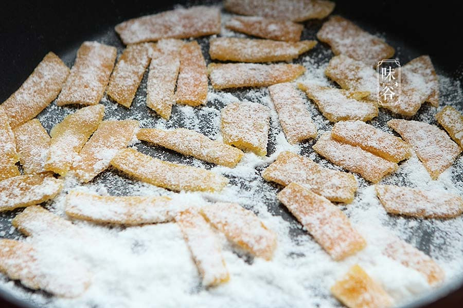 Bề mặt vỏ cam hơi dính. Đổ đường tinh hạt mịn ra đĩa, lăn vỏ cam để phủ đều đường.