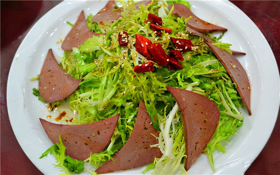 Sau đó, cho rau cúc đắng đã thái vào, cho 1 thìa mắm tỏi và 1 thìa nước tương giấm, dầu ớt vào trộn đều là có thể ăn được rồi. Gan lợn mềm và bổ dưỡng, cúc đắng cũng giúp xua đi cái mệt mỏi.