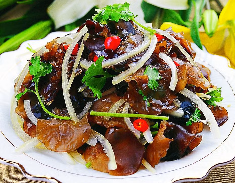 Để làm món này, mộc nhĩ ngâm nở, nhặt rửa sạch, chần qua nước sôi một phút rồi đổ ra, sau đó cho vào nồi trộn, cắt nhỏ hành tím, rắc ngò tây rồi cho một thìa tỏi băm vào. 1 thìa đường, 1 thìa xì dầu, 1 chút tinh chất gà muối và bột ngọt, đảo nhanh tay cho đều rồi bày ra đĩa, vị giòn, béo ngậy.