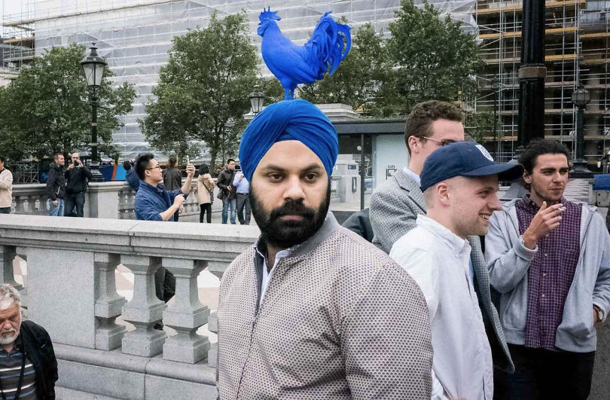 Chiếc mũ khăn của người đàn ông trùng màu với bức tượng con chim màu xanh phía xa. Ở góc chụp này, trông giống như anh ta đang đội cả con chim trên đầu.