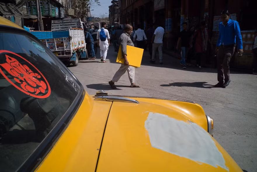 Khoảnh khắc trùng hợp khó tin khi chiếc xe ô tô màu vàng xước sơn đúng một khoảng bằng tấm bảng của người đàn ông đi phía xa đang cầm.