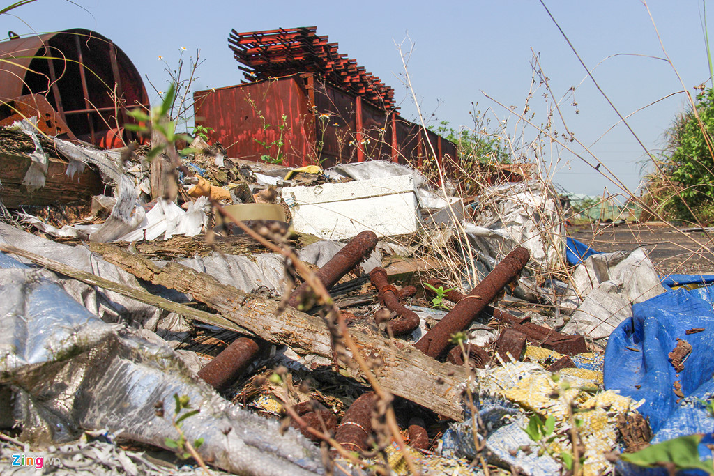 Những đống phế liệu từ vật liệu công trình chắn ngang cả đường đi, giữa cây cỏ um tùm.