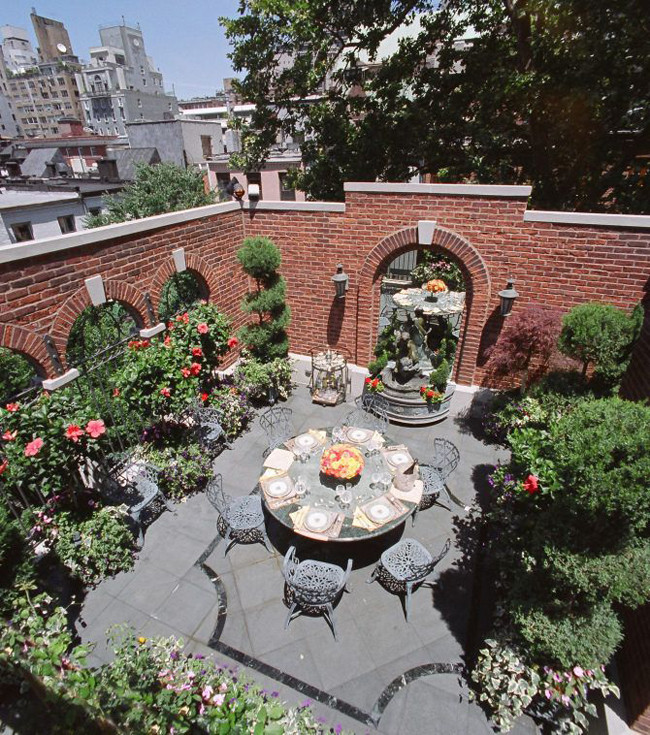 Có một sân vườn được tạo cảnh trên sân thượng, bao quanh bởi các bức tường gạch kiểu cổ.