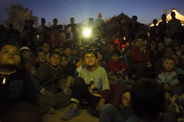 Rất đông trẻ em trong khu trại tị nạn gần làng Idomeni chăm chú xem bộ phim hoạt hình được chiếu trong khu trại.