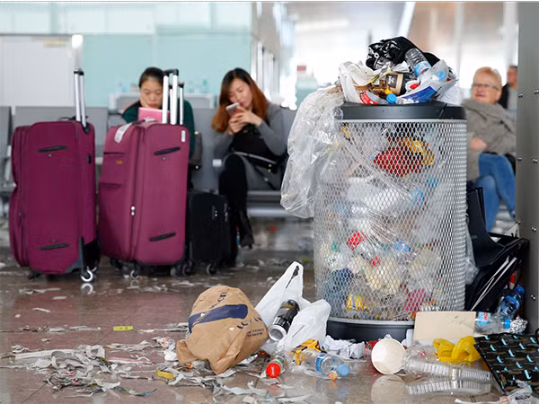 Hành khách ngồi chờ cạnh đống rác ở sân bay Tây Ban Nha.