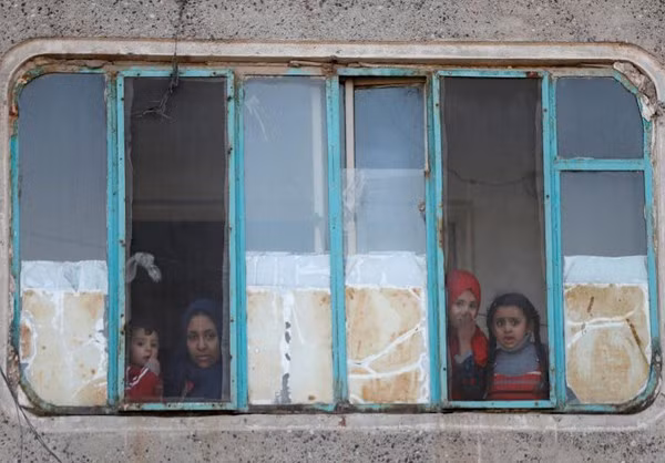Người dân ở thành phố Mosul nhìn ra ngoài cửa sổ.