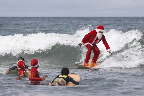 Ông già Noel dạy trẻ em lướt sóng ở bãi biển ở Kuta, Bali, Indonesia. Hàng năm vào tháng 12, các trường dạy lướt sóng ở Bali đều cung cấp các lớp dạy lướt sóng miễn phí cho trẻ mồ côi như một món quà Giáng sinh ý nghĩa.