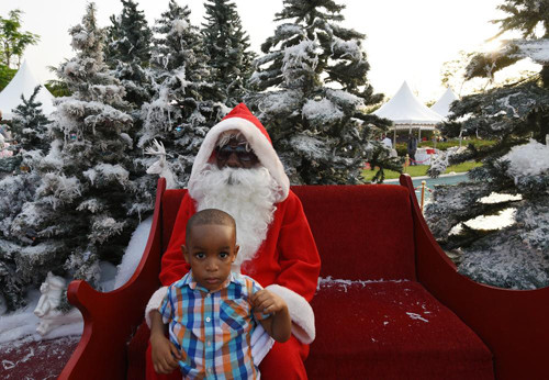 Một cậu bé ngồi với ông già Noel ở khu vườn trong cung điện tổng thống ở Abidjan trong lễ Giáng sinh vừa qua.