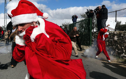 Những người biểu tình Palestine mặc trang phục ông già Noel đụng độ với các binh sĩ Israel ở trạm kiểm soát Bethlehem, khu Bờ Tây do Israel chiếm đóng.