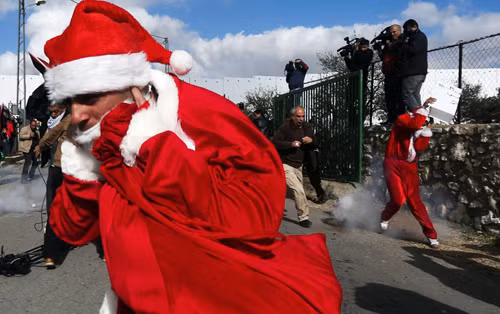 Những người biểu tình Palestine mặc trang phục ông già Noel đụng độ với các binh sĩ Israel ở trạm kiểm soát Bethlehem, khu Bờ Tây do Israel chiếm đóng.