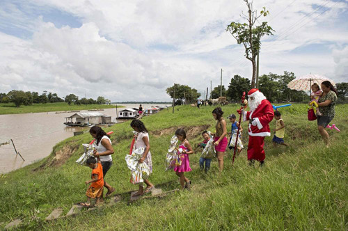 Một thành viên nhóm Amigos do Papai Noel (Những người bạn của nhóm Santa Claus) đi cùng một nhóm trẻ nhỏ sau khi phát quà ở Caneiro da Varzea, bang Amazonas, Tây Bắc Brasil. Nhóm tình nguyện này bắt đầu hoạt động phát quà Giáng sinh cho trẻ em ở khu vực từ năm 1998.