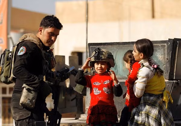 Các em nhỏ Iraq trò chuyện với thành viên của lực lượng Iraq trên đường phố Mosul.