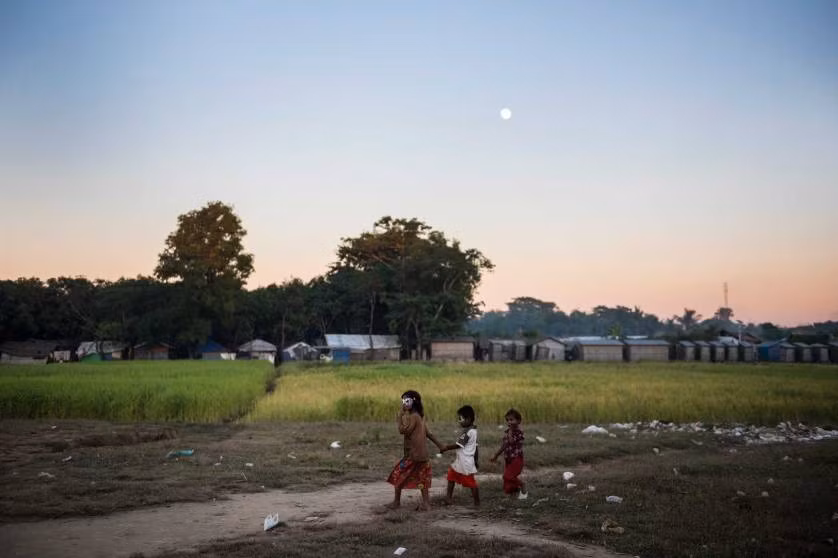 Các em nhỏ tị nạn Rohingya dắt nhau qua cánh đồng đầy rác ở khu trại Thay Chaung ngày 23/11/2015.