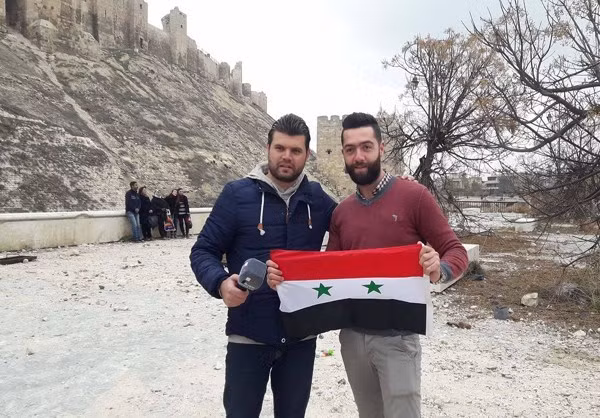 Người đàn ông cầm lá cờ Syria đứng ở khu vực trước Thành cổ Aleppo. (Nguồn ảnh: Fars News Agency)