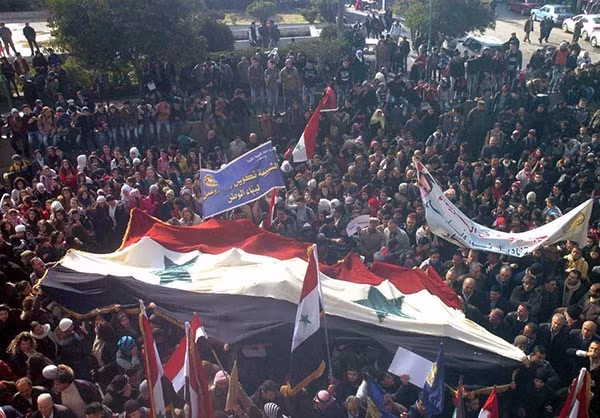 Một lá cờ lớn của Syria được người dân rước trên đường phố Sweida.