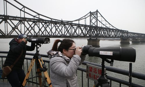 Du khách Trung Quốc ở Đan Đông sử dụng kính thiên văn nhìn về phía Triều Tiên bên sông Áp Lục. (Nguồn ảnh: Global Times).
