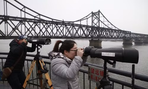 Du khách Trung Quốc ở Đan Đông sử dụng kính thiên văn nhìn về phía Triều Tiên bên sông Áp Lục. (Nguồn ảnh: Global Times).