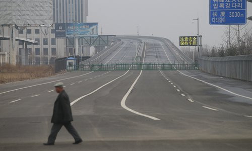 Một người đàn ông đi bộ qua cây cầu Áp Lục mới ở Đan Đông (Trung Quốc). Phần cây cầu phía bên Trung Quốc đã hoàn thành nhưng hoạt động xây dựng cây cầu phía bên Triều Tiên đã phải tạm ngừng do thiếu kinh phí.