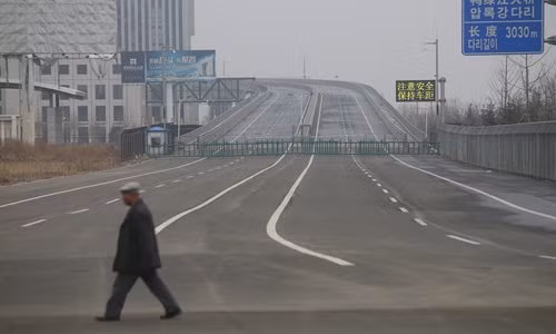 Một người đàn ông đi bộ qua cây cầu Áp Lục mới ở Đan Đông (Trung Quốc). Phần cây cầu phía bên Trung Quốc đã hoàn thành nhưng hoạt động xây dựng cây cầu phía bên Triều Tiên đã phải tạm ngừng do thiếu kinh phí.