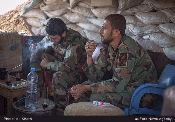 Hai binh sĩ ngồi hút thuốc tại một chốt kiểm soát trong thị trấn.