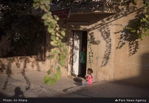 Một em nhỏ Syria ngồi trước cửa nhà.