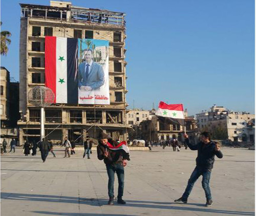 Bức ảnh Tổng thống Bashar al-Assad được treo cạnh lá cờ Syria trên một tòa nhà cao tầng ở thành phố Aleppo. Ảnh: LAT.