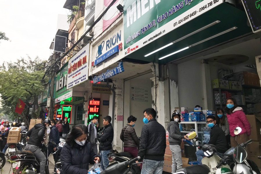 Do lượng khách quá đông nên nhiều nhà thuốc đã phải bố trí từ 4 đến 6 nhân viên vừa dắt xe máy, vừa bán bán khẩu trang cho khách.