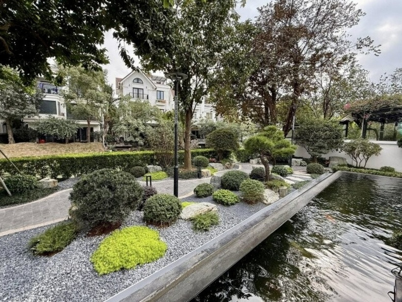 Hàng cây cao lớn được trồng dọc theo lối đi trong khuôn viên, tạo bóng mát tự nhiên. Bên cạnh đó, gia đình còn thiết kế hệ thống đèn trụ trang trí hoa văn cổ điển, giúp không gian sân vườn trở nên sang trọng và lung linh hơn vào buổi tối.