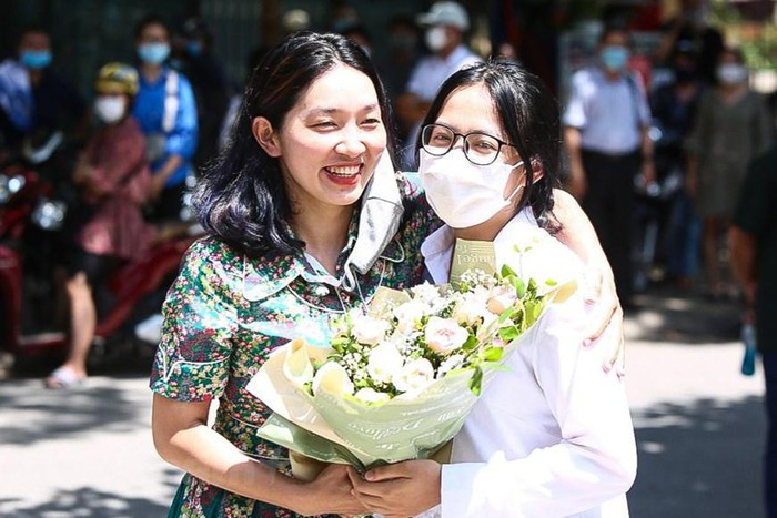 Trong ảnh, một phụ huynh chuẩn bị sẵn bó hoa để chúc mừng con gái hoàn thành bài thi. Người mẹ này vui sướng hơn khi biết con mình làm tốt các bài thi. (Ảnh: Phúc Tá/Vietnam+)