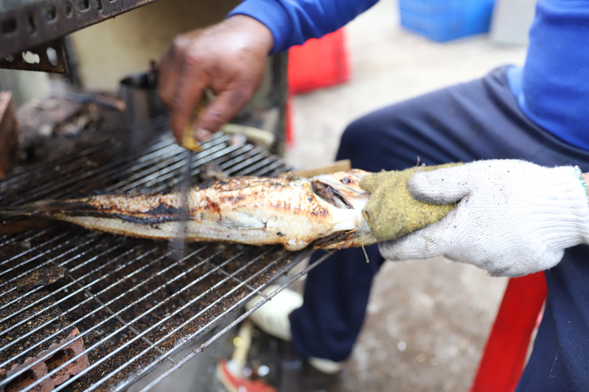 Những con cá lóc nướng cháy xém lớp vảy bên ngoài, khi cạo đi để lộ phần da vàng ươm hấp dẫn. Cá sau khi nướng được đặt lên mẹt, kèm theo rau sống, bún và mắm nêm – món ăn đặc trưng trong ngày vía Thần Tài.