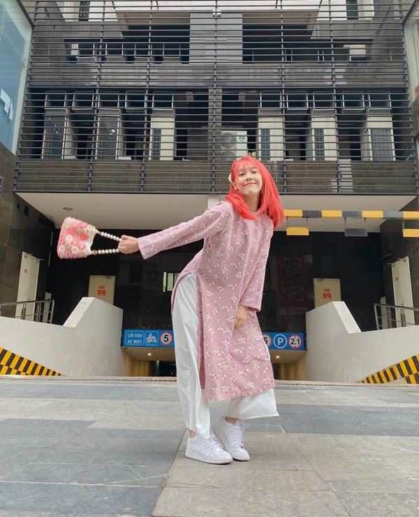 Cụ thể, nữ Youtuber diện áo dài màu hồng nhạt, họa tiết hoa nhí. Cô nàng phối với túi xách màu tương đồng, tóc nhuộm màu nổi “thương hiệu”.