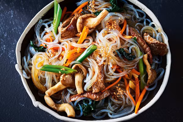 Japchae (mì xào Hàn Quốc). Japchae được làm từ mỳ thủy tinh (tương tự như miến). Đầu tiên, mỳ được trụng chín. Sau đó vớt ra trộn với cà rốt, hành tây, rau bina, nấm cắt sợi, đôi khi có cả thịt bò. Mì xào có thể dùng nóng hoặc lạnh.
