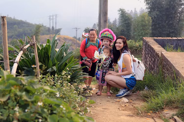Á hậu Hoàng My chụp ảnh cùng 2 em bé đang trên đường đến chợ phụ mẹ bán búp bê ở Sapa.