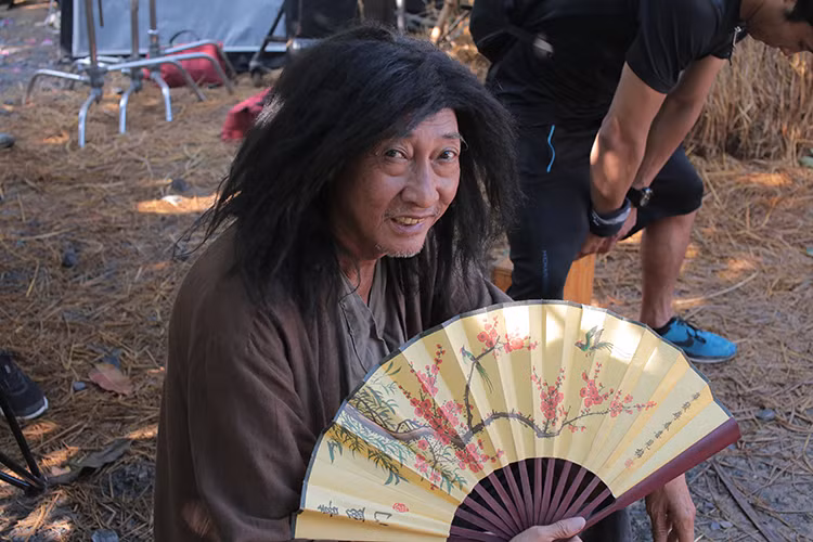 Nội dung phim “798Mười” xoay quanh câu chuyện về một anh bán bánh tiêu bị mất người yêu vào tay một trùm giang hồ thế lực, chẳng biết trông cậy vào ai nên đành lôi người bạn thân nhất vào cuộc, nhưng oái oăm thay, anh bạn thân lại bị mù, ở quê lần đầu lên thành phố cùng với một con vịt cưng. Trong ảnh, nghệ sĩ Lê Bình đóng vai sư phụ Bành.