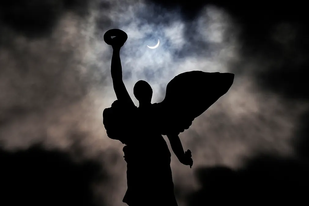 Hình ảnh nhật thực diễn ra đằng sau tượng thiên thần trên đỉnh Cổng Hoàng tử, ở Toronto. Ảnh: The Canadian Press.