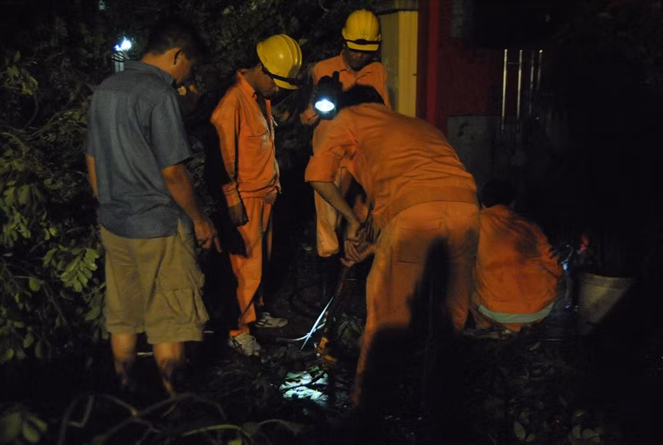 Điện lưới mất, lực lượng Công ty điện lực Hà Nội dùng đèn pin chiếu sáng để khắc phục hậu quả sau cơn mưa giông, lốc xoáy.