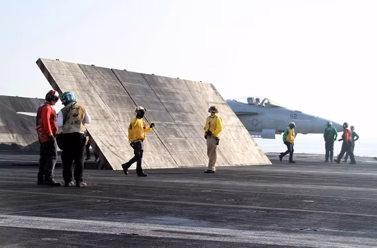 Mỗi kỹ thuật viên hoạt động trên boong tàu sân bay đều liên lạc với nhau qua thiết bị bộ đàm được gắn sẵn trên mũ bảo hiểm và mỗi bộ phận hổ trợ đều được phân màu áo khác nhau.