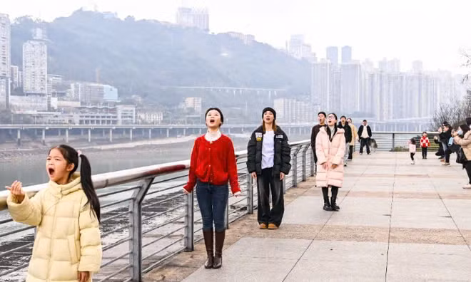 Người chụp cần kết hợp ăn ý, lựa chọn vị trí phù hợp, để bức ảnh hoặc góc quay trùng với thời điểm chuyến tàu "chui tọt" vào miệng người được chụp. Ảnh Chongqing Daily