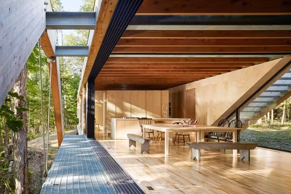 Một sàn gỗ liên kết các dầm lại với nhau, tạo cho ngôi nhà có dạng hình thang và một cây cầu bắc ngang qua hẻm núi ở mặt tiền ngôi nhà.