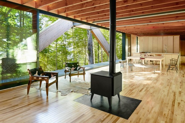 Nhà bếp và phòng khách nằm ở trung tâm của ngôi nhà. Nội thất bên trong khá tối giản, gọn nhẹ đa phần làm bằng gỗ để phù hợp với thiết kế. Một lò sưởi nhỏ màu đen được đặt chính giữa là điểm nhấn cho căn phòng. Sàn nhà làm bằng gỗ phong với màu sáng giúp tăng thêm sự ấm cúng. Trần nhà lộ gỗ đem lại cảm giác mộc mạc nhưng đầy tinh tế, thân thiện với thiên nhiên.