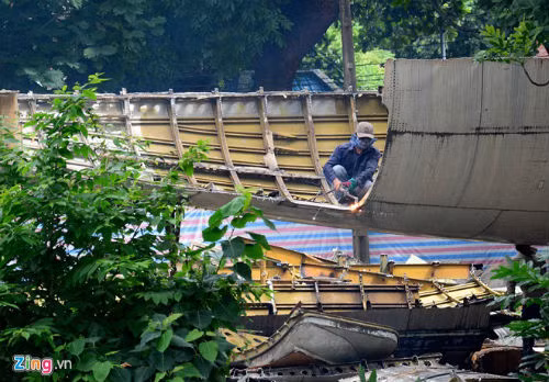 Một công nhân ngồi trong bụng máy bay cắt từng mảng thân 2 bên.