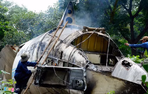 Hai công nhân tập trung xử lý từng bộ phận nhỏ của đuôi máy bay. Họ phải dùng thang leo lên để làm việc