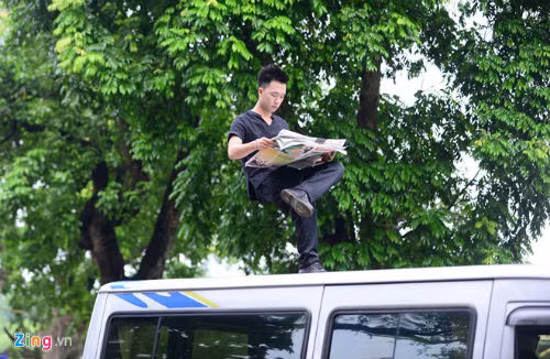 Chàng trai 9X ngồi một chân, trên tay đọc tờ báo giấy, phía dưới Nam không có vật gì.