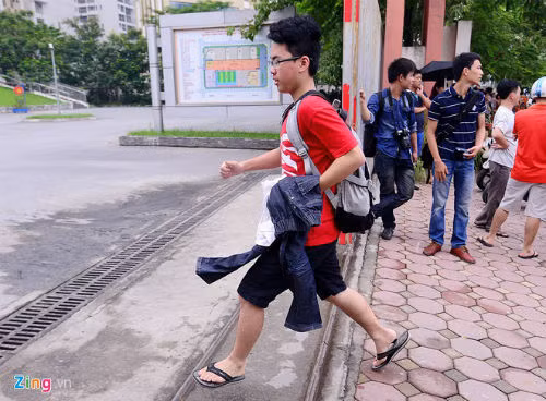 Một thí sinh nam sau khi được bố mẹ mang quần dài đến, vội vã chạy vào trường để thay trang phục.