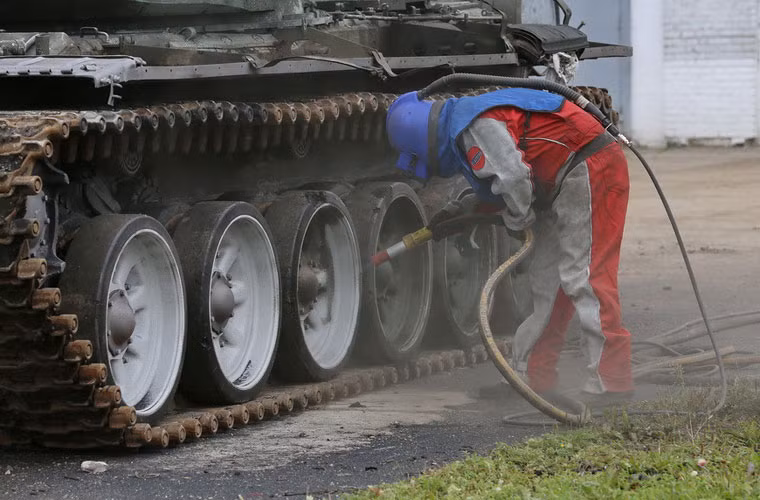 Tiếp đó, một nhân viên sẽ dùng thiết bị phun đặc biệt để xóa lớp sơn ngụy trang cũ.