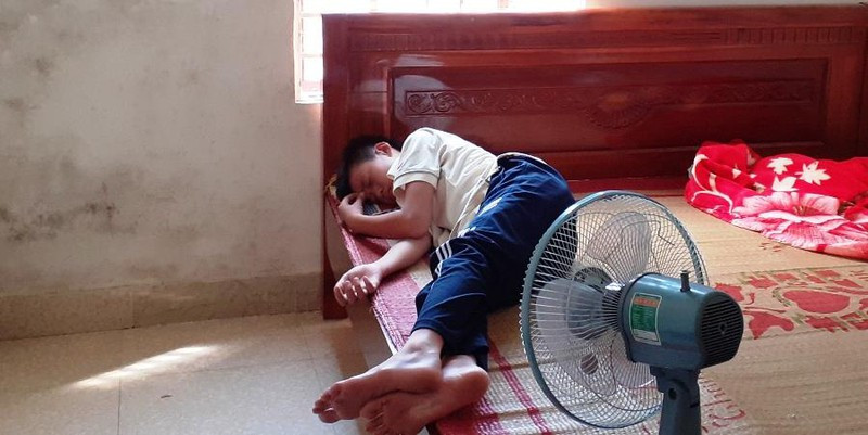 Ngư dân nhí Trần Văn Cường nằm nghỉ sau khi về đến nhà trong vòng tay người thân. Hiện người cậu ruột của Cường là ông Đậu Ngọc Cầm và ngư dân Trần Quang Thiện (trú xã Sơn Hải) đang mất tích.