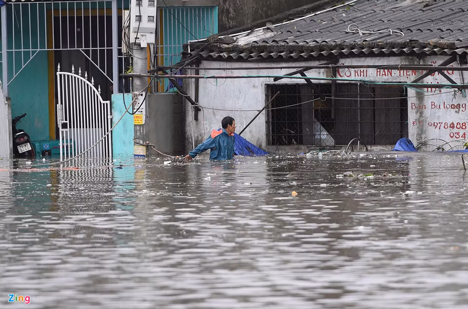 Lúc này nước đã ngập tận bụng người lớn. Một người đàn ông dò dẫm vào nhà cứu vớt đồ đạc bị chìm sâu. Ảnh: Tiến Tuấn.