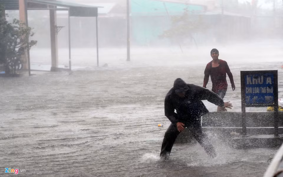 Nhiều thời điểm gió giật mạnh, nhiều người vẫn cố chống chọi để dọn dẹp trước cửa nhà. Ảnh: Tiến Tuấn.