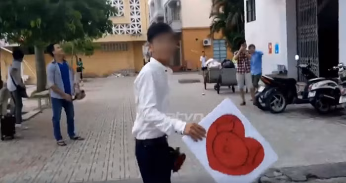 Cô bạn tầng 3 chẳng những không đồng ý mà còn hất nguyên một chậu nước vào chàng trai này nhưng không trúng. Không bỏ cuộc, chàng trai tiếp tục giơ bảng có hình trái tim cùng đóa hoa hồng và lần này, đã bị chậu nước thứ 2 làm cho ướt hết... Ảnh cắt từ clip.